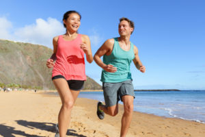 man and woman running on the beach
