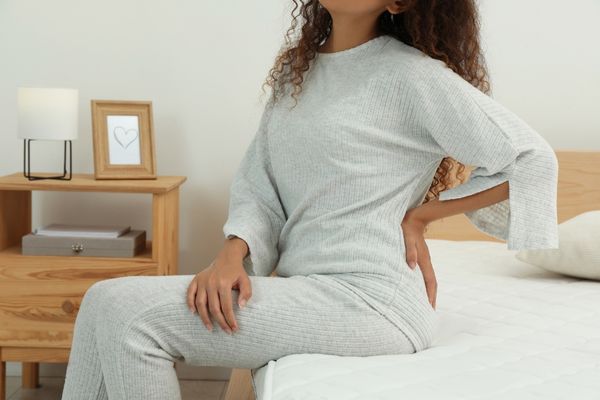 woman sitting on a bed with back pain