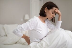woman suffering from back pain in bedroom