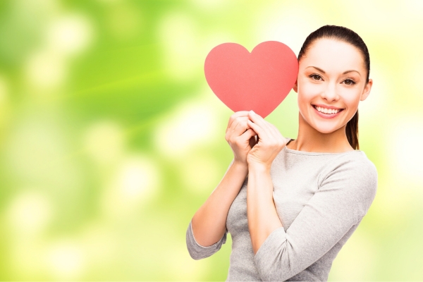 smiling woman holding heart shape